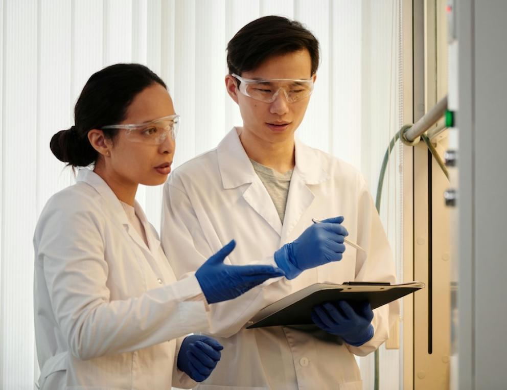 Two research scientists wearing protective gear in a lab.