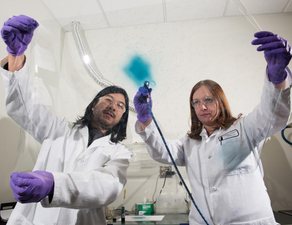 Senior Research Scientist Eric Shen (left) and Principal Research Scientist Anna Österholm (right) demonstrate how films of electrochromic polymers can be applied to large surfaces.